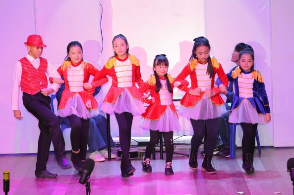 A group of young girls dancing on a stage AI-generated content may be incorrect.